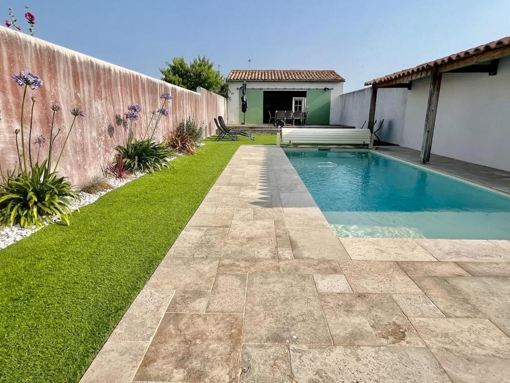 a backyard with a swimming pool and green grass at Villa avec Piscine chauffée, a 5mn de la plage in Sainte-Marie-de-Ré