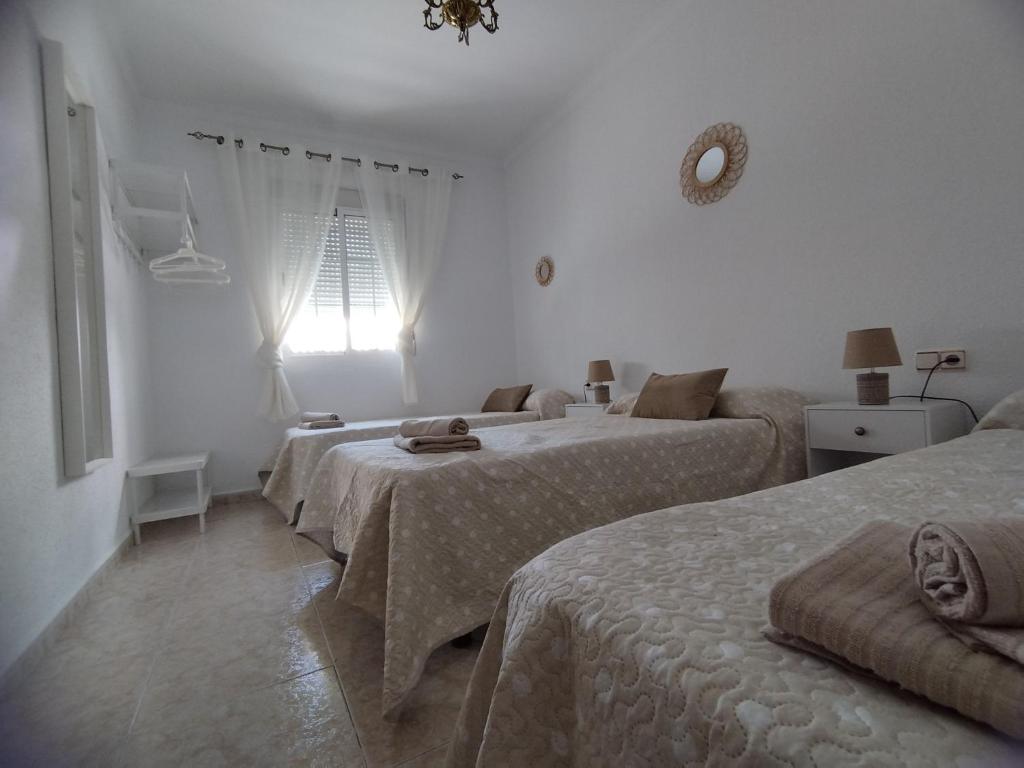 a bedroom with three beds and a window at Casa Paco & Carmela in Algodonales