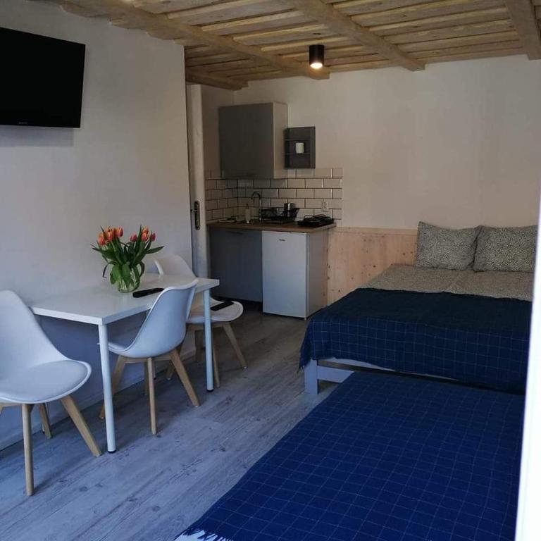 a bedroom with a bed and a table and a kitchen at Krutyńska Sielanka in Piecki