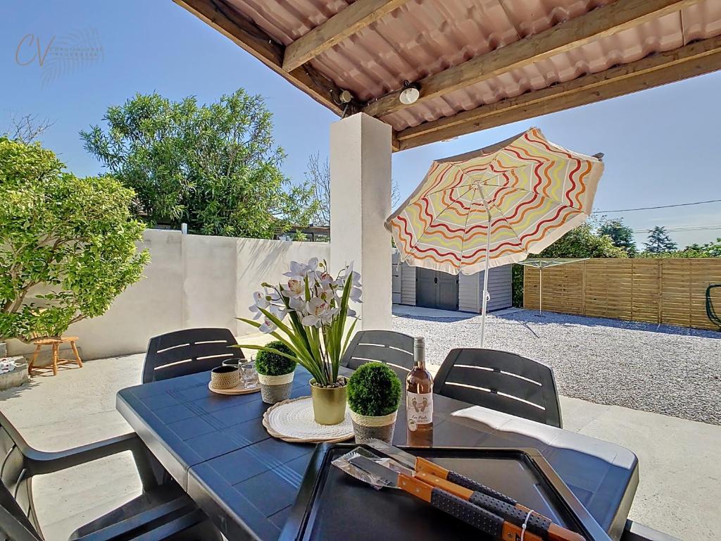 une table avec des chaises et un parasol sur une terrasse dans l'établissement Maison La Corsica - Vias Village, à Vias