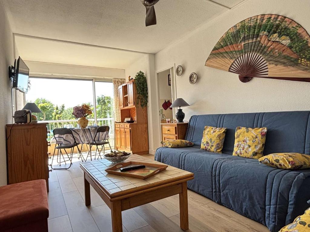 un salon avec un canapé bleu et une table dans l'établissement Appartement 2 pièces/cabine, près de la plage avec loggia - Parking privé, TV, lave-linge & lave-vaisselle - FR-1-225-85, à Argelès-sur-Mer