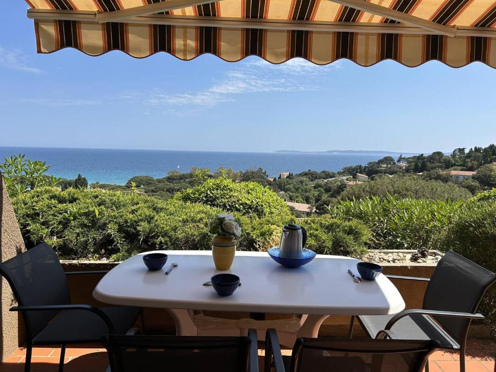 une table blanche et des chaises sur un balcon avec l'océan dans l'établissement T2 Cabine au Lavandou - Vue Mer, Parking Privé - FR-1-251-858, au Lavandou