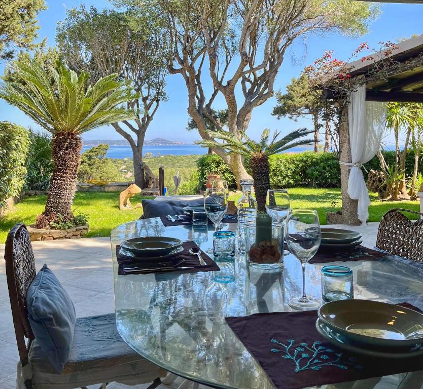 a glass table with plates and wine glasses on it at Bellavista Porto Rotondo in Porto Rotondo