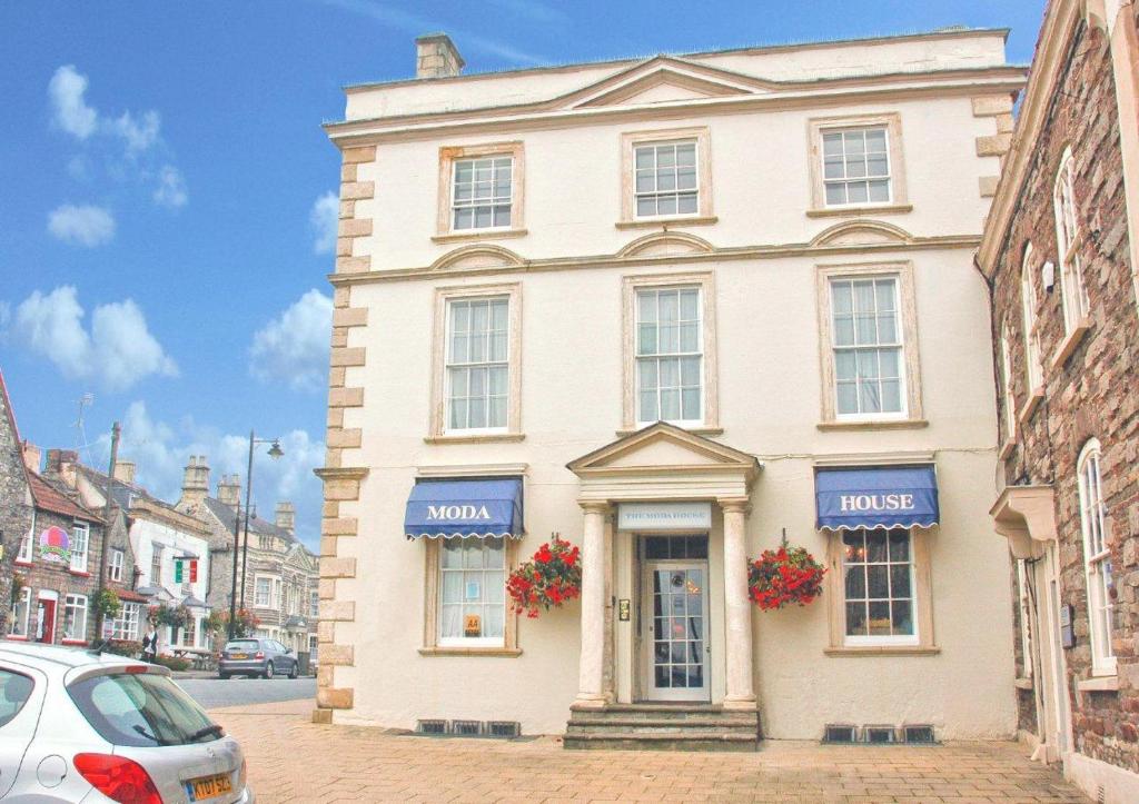 a white building on a street with cars parked in front at The Moda House in Chipping Sodbury