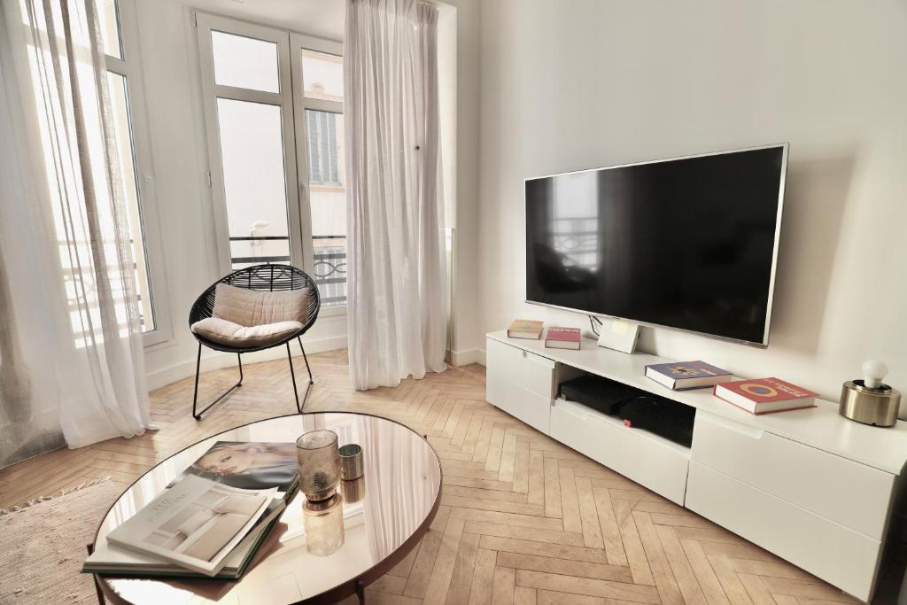 un salon avec une télévision et une table en verre dans l'établissement Chic 1-bedroom apartment steps away from La Croisette, à Cannes