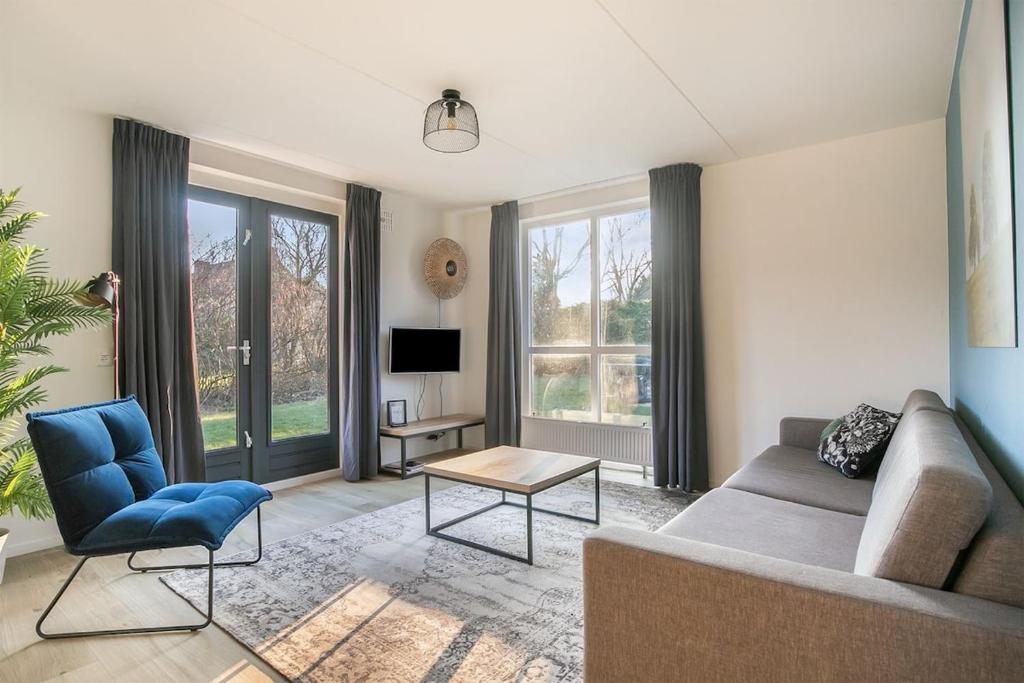 a living room with a couch and a table at Zeer comfortabel vakantiehuis op kleinschalig park 6 personen in Ewijk