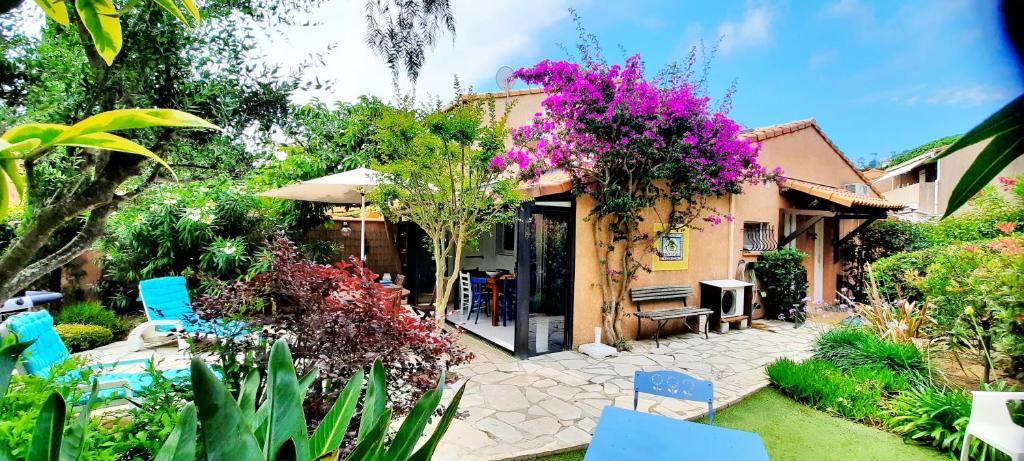 un jardin avec une maison ornée de fleurs violettes dans l'établissement LE MAZET DU SOLEIL D'OR à 300m plage Nartelle, à Sainte-Maxime