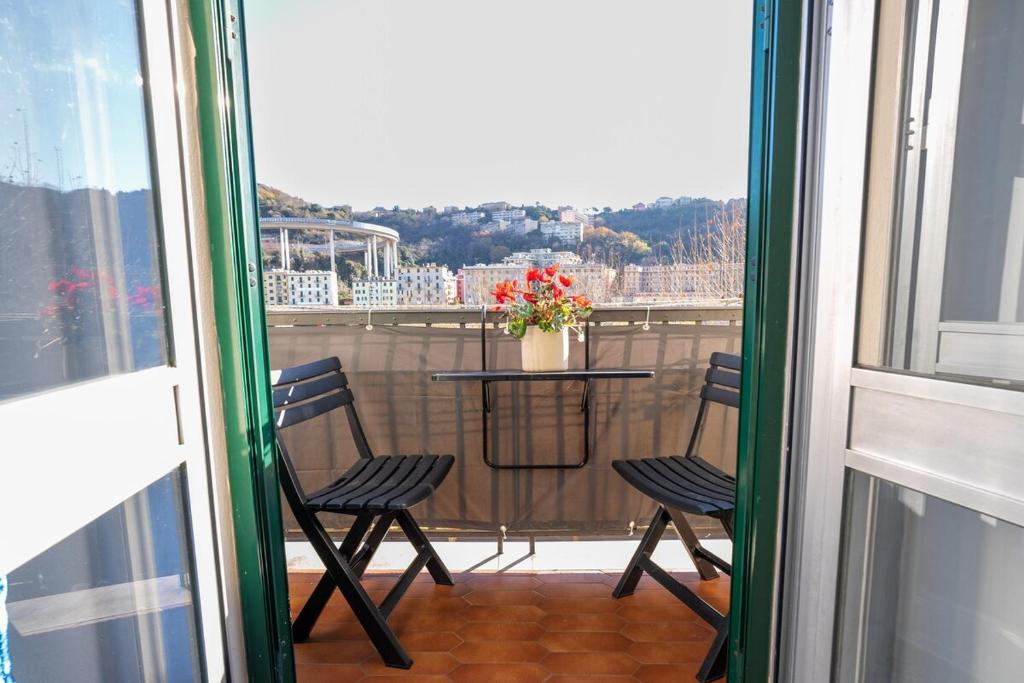 a balcony with two chairs and a table with flowers at Casa Giorgia with Parking Space in Genoa