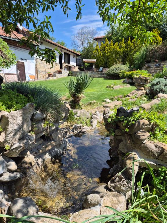 a pond in a garden with rocks andgrass at Chamurkov Guest House in Veliko Tŭrnovo