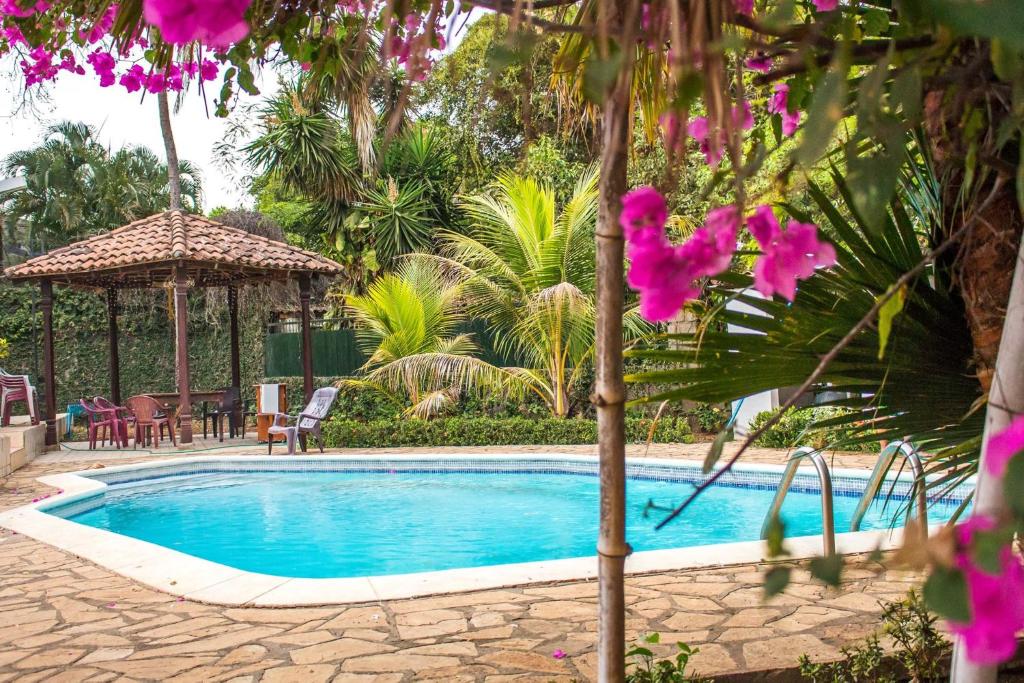 una piscina en un patio con flores púrpuras en Casa Inti Guesthouse & Lodge, en Managua