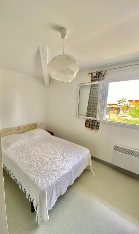 une chambre blanche avec un lit et une fenêtre dans l'établissement Charmante maison plage, à Contis-les-Bains