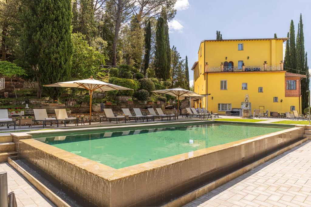 a swimming pool with chairs and umbrellas next to a building at Tenuta Villa Febea in Chiusi