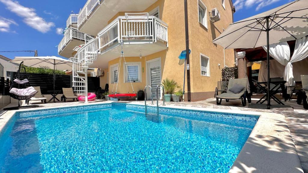 a swimming pool in front of a house at Apartman Stipić 2 in Kaštela