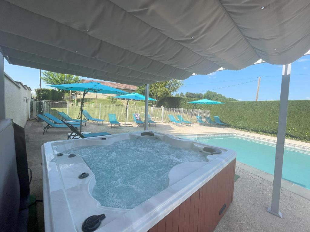 - un bain à remous sous un parasol à côté de la piscine dans l'établissement Bienvenue Vacances Sarlat-La-Canéda, à Proissans