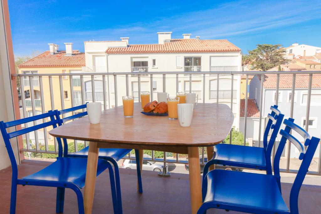 une table en bois avec des chaises et une assiette de nourriture sur un balcon dans l'établissement Mezzanino by POM, pkg, mezzanine, au Cap d'Agde