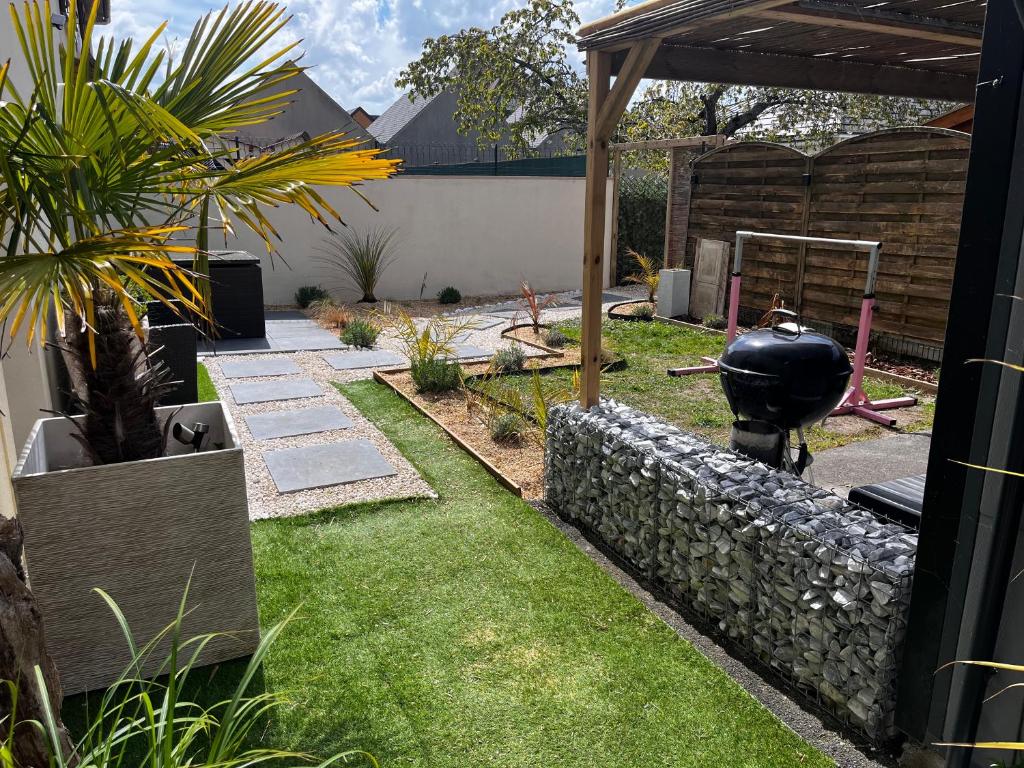 un jardin avec un mur en pierre et un grill dans l'établissement Villa Mela-Bella, à Ouistreham