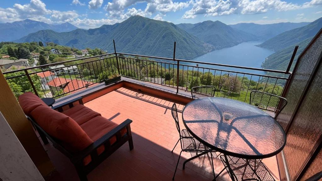 a glass table and chairs on a balcony with a view at VillaMarinaPigra Lake View Apartments in Pigra