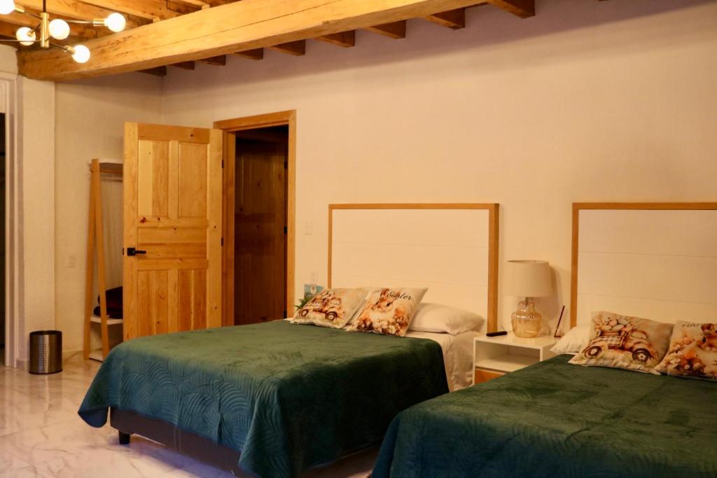 ein Schlafzimmer mit zwei Betten mit grüner Bettwäsche und einer Tür in der Unterkunft Veta Corona in Tlalpujahua