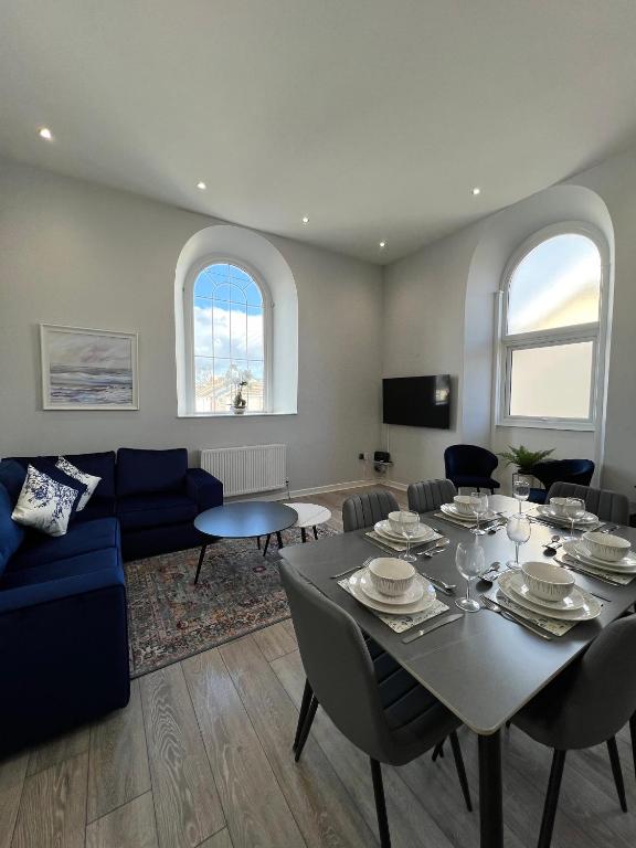 a living room with a table and a blue couch at Welsh Getaway Apartment - Town Centre in Merthyr Tydfil