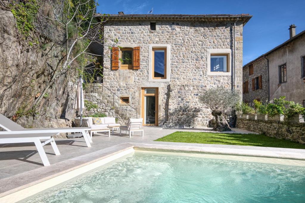 a stone house with a swimming pool in front of it at le prieuré in Vals-les-Bains