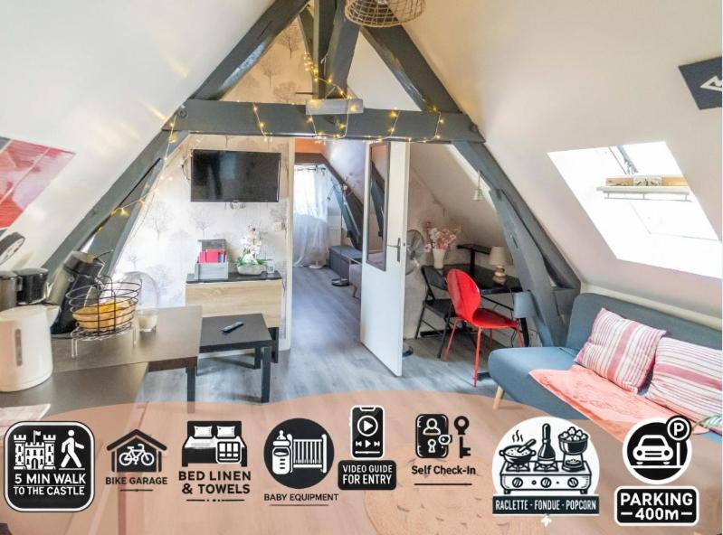 Cette chambre mansardée comprend un canapé et une table. dans l'établissement L'ETOILE DE BLOIS Appart Hyper Centre Château Gare à 5min, à Blois