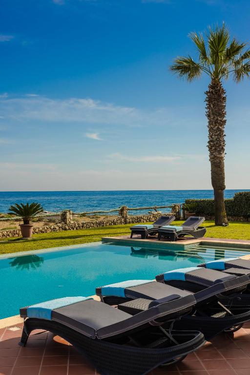 a swimming pool with lounge chairs and a palm tree at Villa Sunset in Argostoli