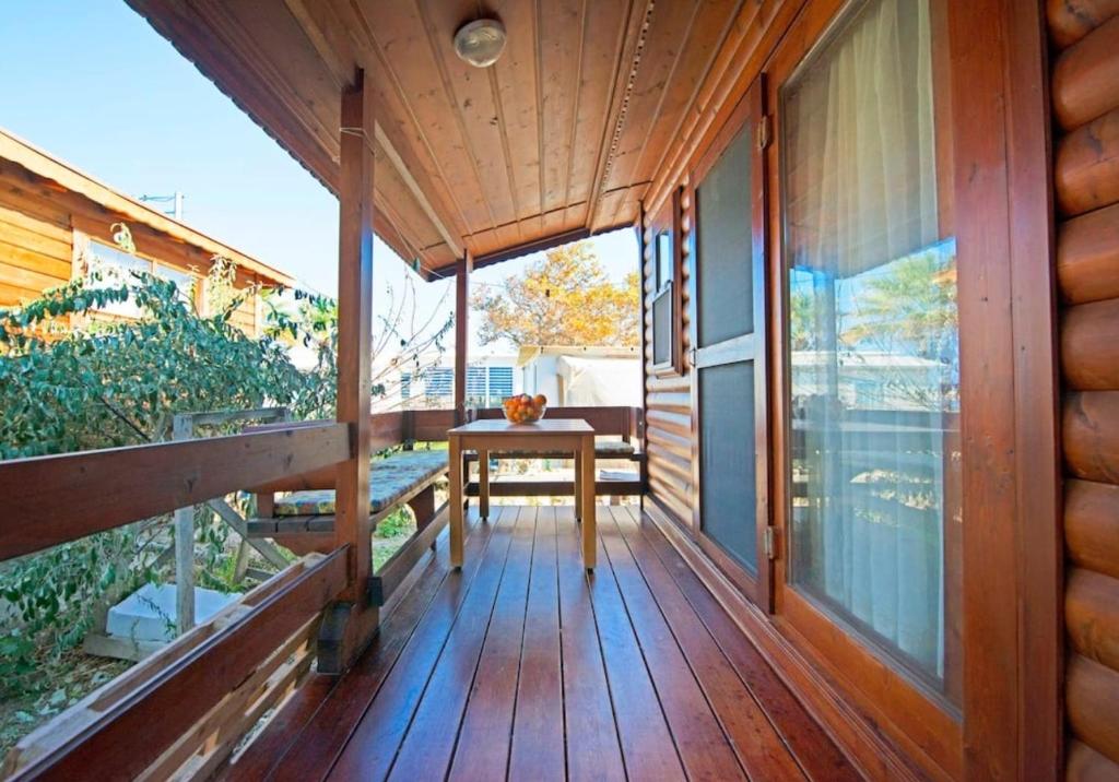 una veranda in legno di una casa con un tavolo sopra di Yeniliman Bungalov Evleri- Sümbül Adlı Ev -Karaburun -İzmir a Karaburun