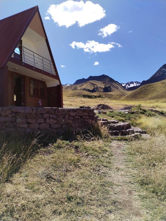 a building with a stone wall next to a field at Apu Tacllo lodge in Layo