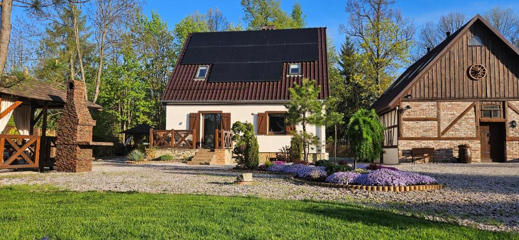 dom z czarnym dachem i ogródkiem z kwiatami w obiekcie Apartamenty Komarno 46 Jacuzzi&Sauna w mieście Komarno