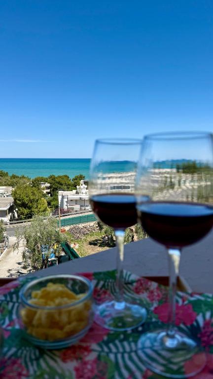 due bicchieri di vino su un tavolo con vista sulla spiaggia di Ibisco Hotel a Rodi Garganico
