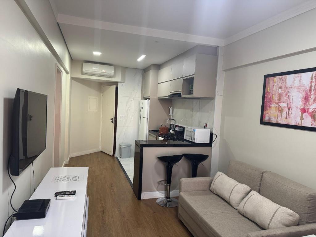 a small living room with a couch and a kitchen at Flat mobiliado 45 - L Hirondelle in Campinas