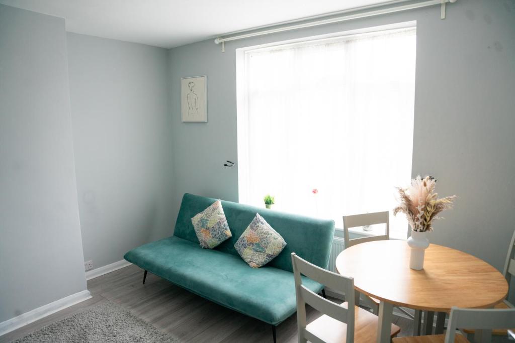 a living room with a green couch and a table at Modern London House With Free Parking & Family Friendly in Edgware