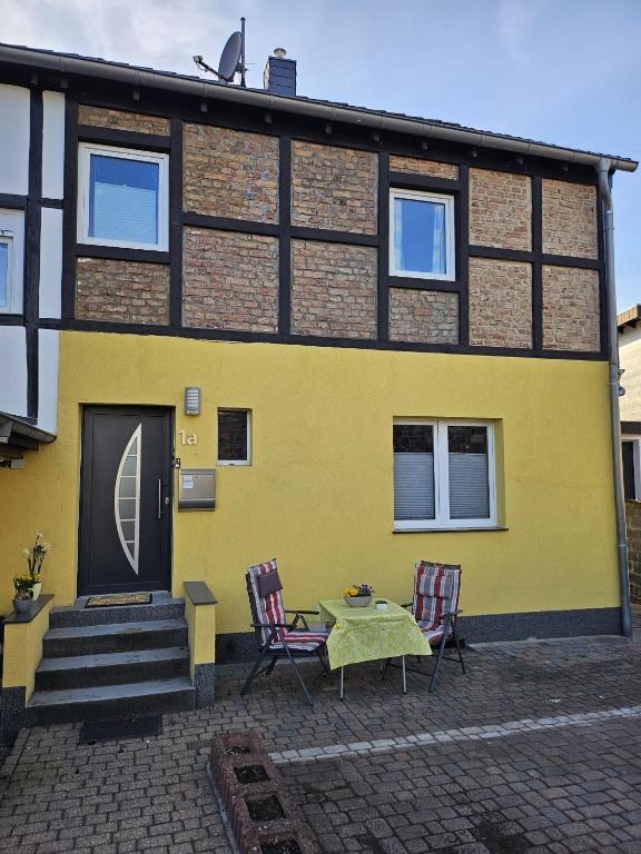 a yellow house with two chairs and a table in front of it at Ferienhaus Doris in Heimbach