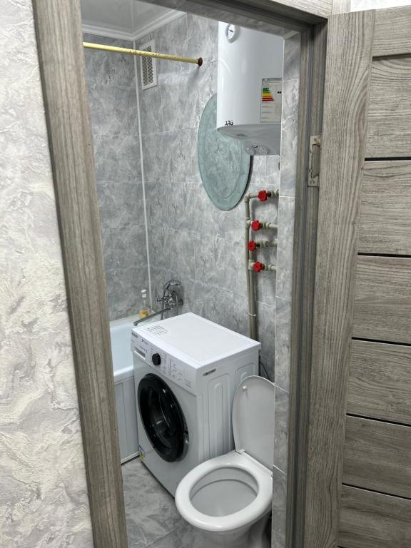 a bathroom with a toilet and a washing machine at Двухкомнатная квартира в центре города Сейфуллина 33 in Balqash