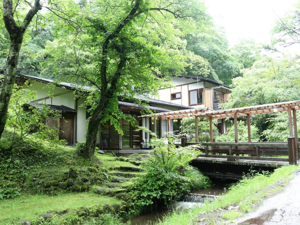 a house with a bridge next to a river at Kose Onsen in Karuizawa