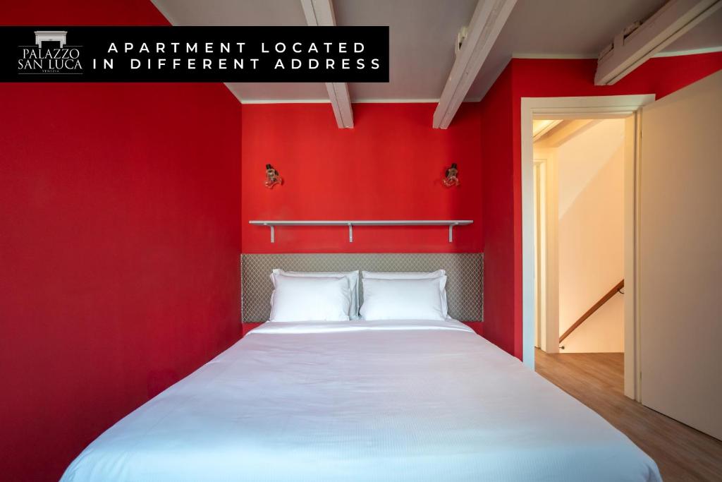a red bedroom with a bed with white sheets at Palazzo San Luca in Venice