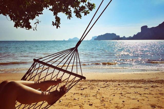 a woman sitting in a hammock on a beach at Dawn of Happiness in Ao Nam Mao