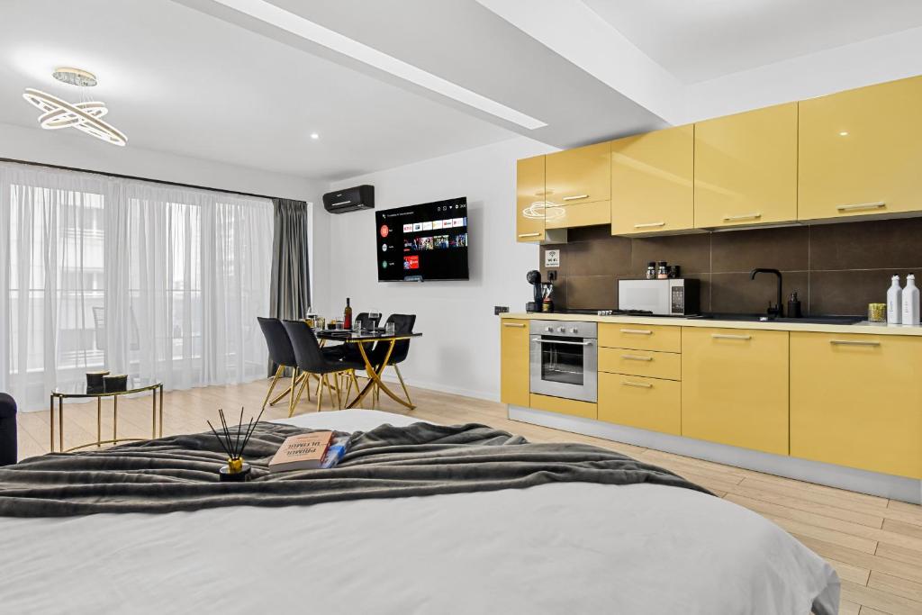 a room with a bed and a kitchen with yellow cabinets at InCity Studio - Near Bucharest Mall, Balcony - RH Living in Bucharest