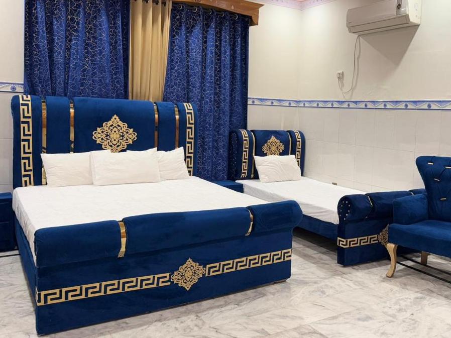 a room with two beds and a blue couch at Istanbul Inn in Islamabad