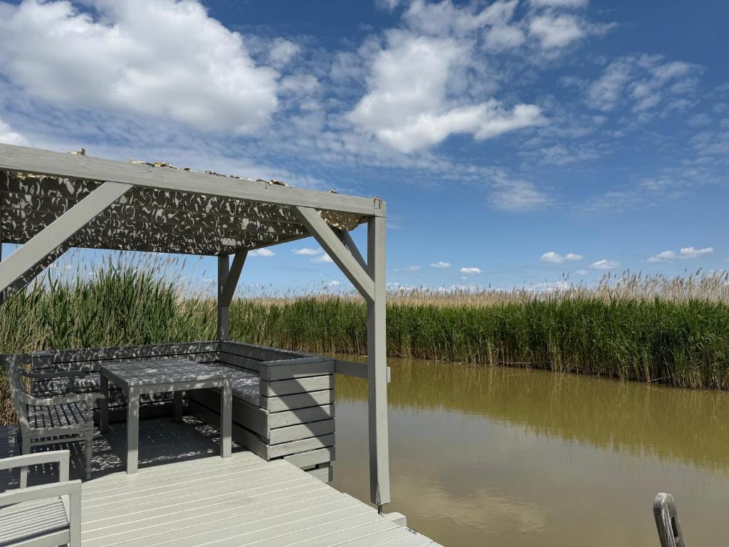 a dock with a bench next to a body of water at Seehütte Neusiedlersee inklusive Boot in Rust