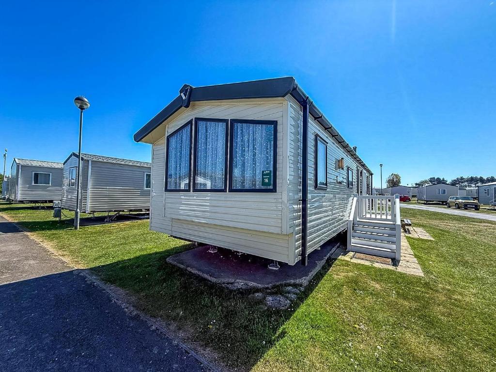 a tiny house is sitting on the grass at 8 Berth Caravan With Decking At Caister Beach In Norfolk Ref 30016S in Great Yarmouth