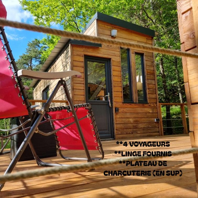 une petite maison avec une balançoire rouge devant dans l'établissement Tiny house en pleine nature, à Arsac-en-Velay