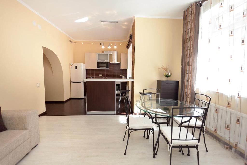 a living room and kitchen with a glass table and chairs at Apartment Grand Kazan near Kremlin in Kazan