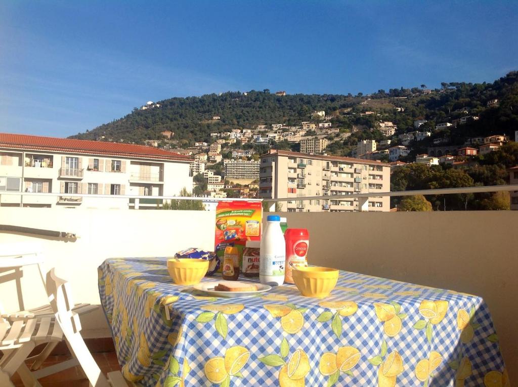 une table avec de la nourriture et des boissons sur un balcon dans l'établissement Studio climatisé au calme, terrasse vue colline, à Nice