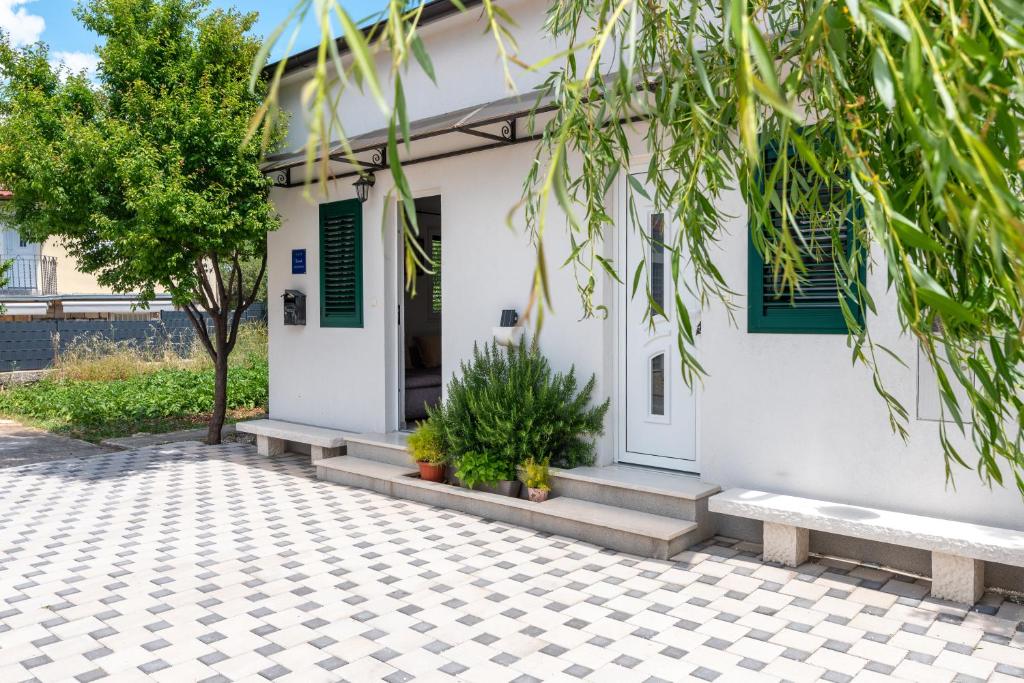 a white house with green shutters and a courtyard at Apartman Donadina-Dalmatian heritage house in Trogir