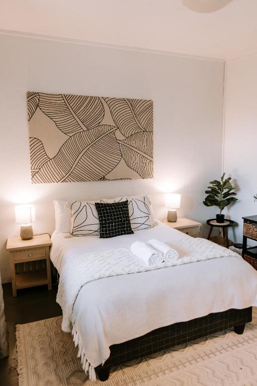 a bedroom with a large white bed with two lamps at Platteland Cottage in Clarens