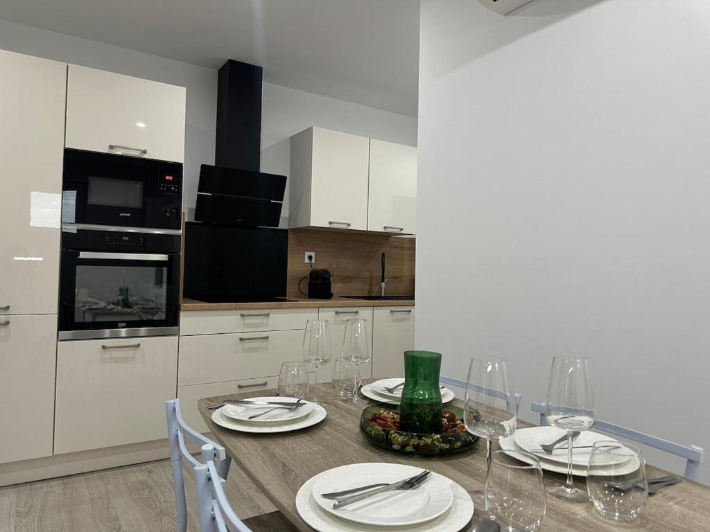une cuisine avec une table avec des assiettes et des verres à vin dans l'établissement Appartement cosy parking privé, à Tarbes