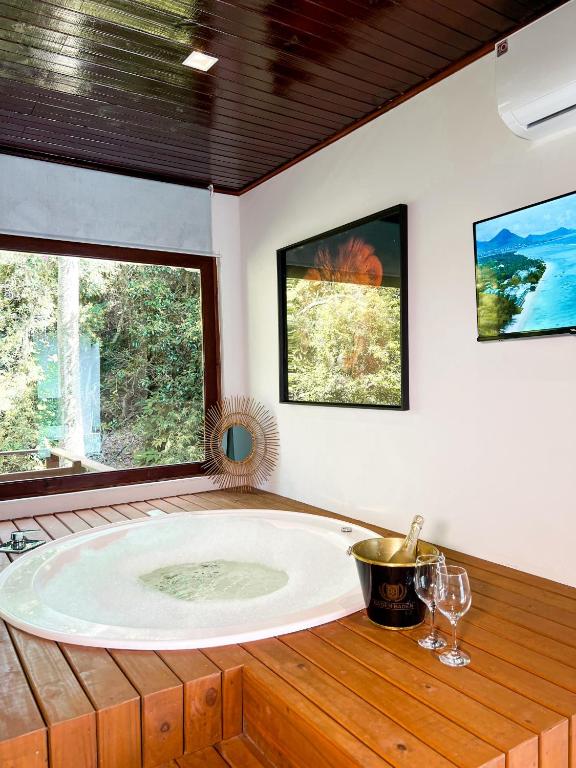 a large tub in a room with two windows at Essência do Sol Pousada in Florianópolis