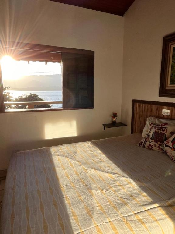 a bedroom with a large bed and a window at Casa amarela in Cambaquara