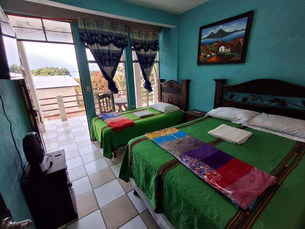 Un dormitorio con dos camas y una gran ventana. en Hotel y Restaurante Pinocchio, en San Pedro La Laguna